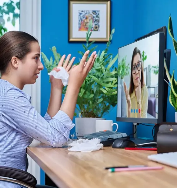 Woman in virtual therapy session on a computer, surrounded by plants.