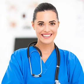 Smiling healthcare professional in blue scrubs with a stethoscope.