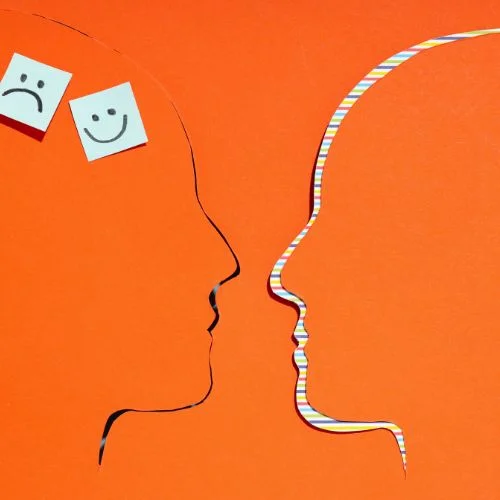 Silhouette of two outlined faces with sad and happy sticky notes.