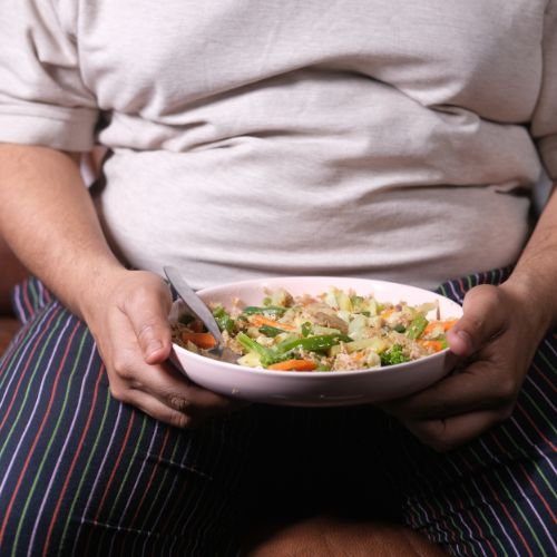 Person holding a bowl of salad with vegetables and chicken.
