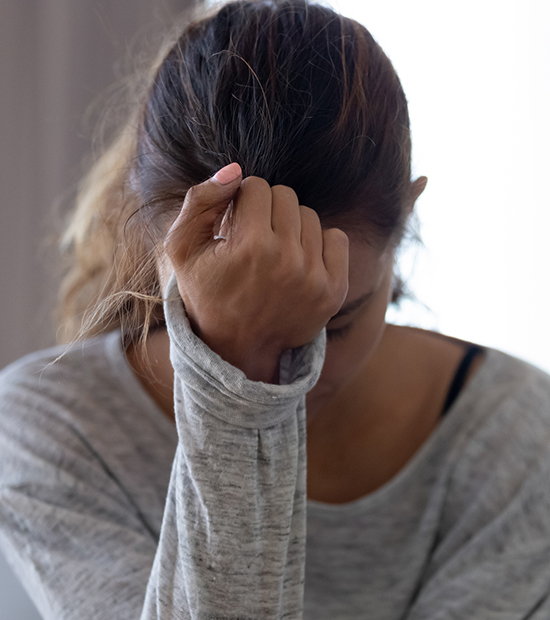 Woman holding her head with her hand, appearing stressed.