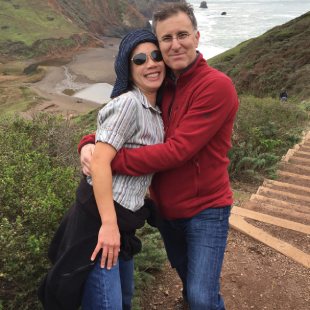 Couple embracing on coastal hillside with ocean in the background.